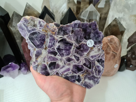 A hand holding a large Chevron Amethyst crystal slice that is approximately 18.5 centimetres by 12.5 centimetres in size