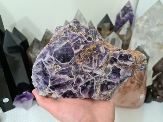 A hand holding a large Chevron Amethyst crystal slice that is approximately 18.5 centimetres by 12.5 centimetres in size