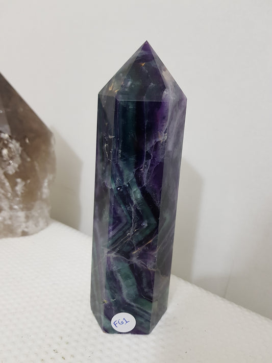 A polished Fluorite crystal generator that stands upright at approximately 16 centimetres tall and 5 centimetres wide