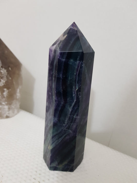 A polished Fluorite crystal generator that stands upright at approximately 16 centimetres tall and 5 centimetres wide