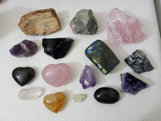 An assortment of mixed natural and polished crystals layed out on a table