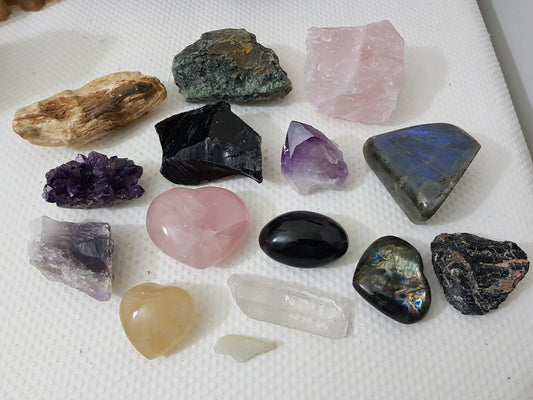 An assortment of mixed natural and polished crystals layed out on a table