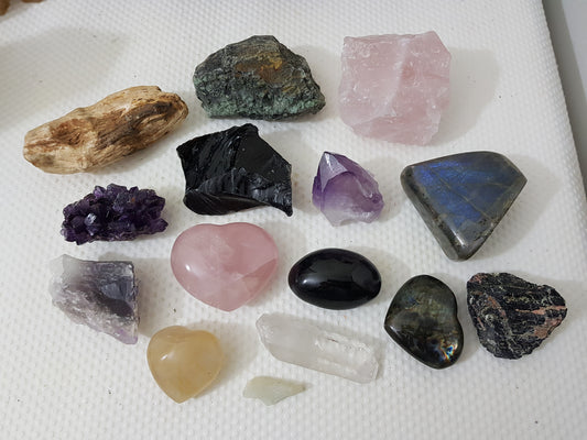 An assortment of mixed natural and polished crystals layed out on a table