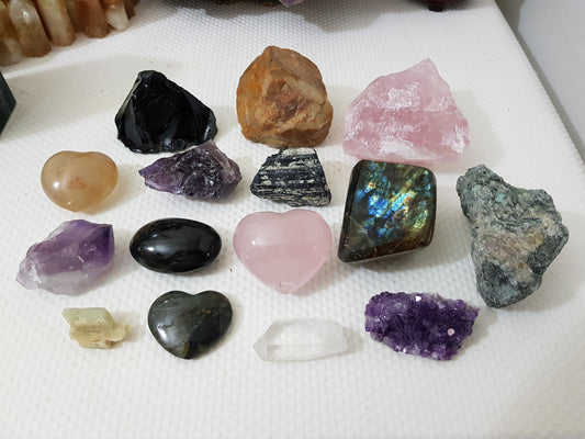 An assortment of mixed natural and polished crystals layed out on a table