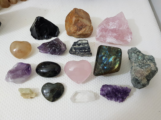 An assortment of mixed natural and polished crystals layed out on a table