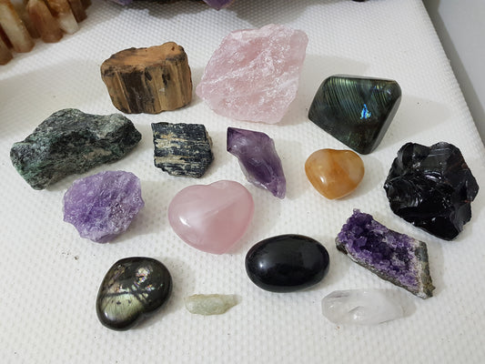 An assortment of mixed natural and polished crystals layed out on a table