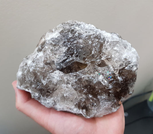 A hand holding a large natural Smoky Quartz crystal that is approximately 13 centimetres by 11 centimetres in size