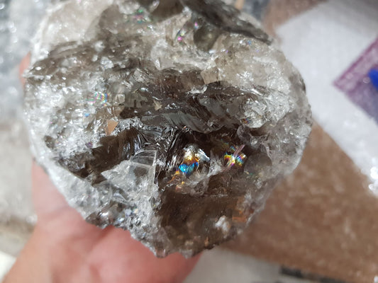 A hand holding a large natural Smoky Quartz crystal that is approximately 13 centimetres by 11 centimetres in size