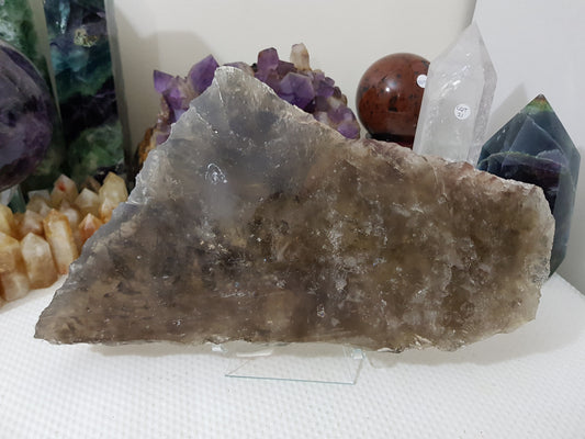 A Smoky Quartz crystal slice that is approximately 33 centimetres by 18 centimetres in size resting on a display stand