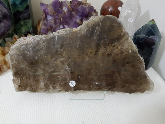 A Smoky Quartz crystal slice that is approximately 33.5 centimetres by 18 centimetres in size resting on a display stand